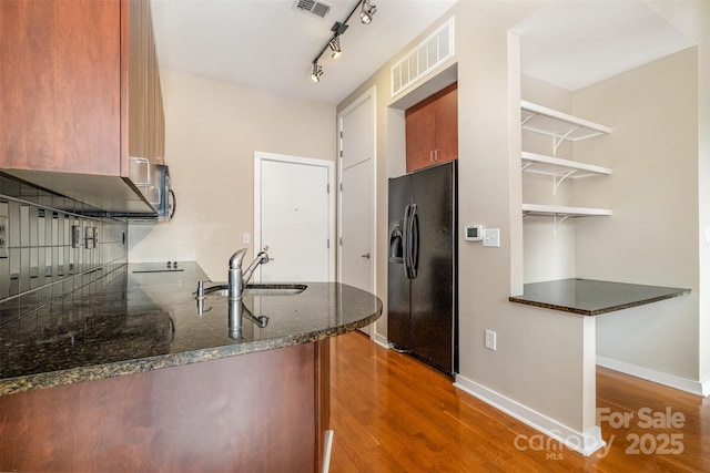 kitchen with dark wood-style floors, black fridge with ice dispenser, visible vents, and a sink