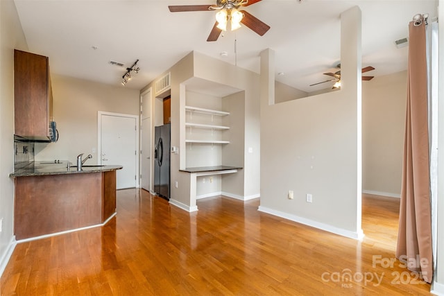 kitchen with black fridge, light wood-style floors, rail lighting, baseboards, and ceiling fan