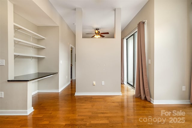 interior space with baseboards, wood finished floors, and a ceiling fan