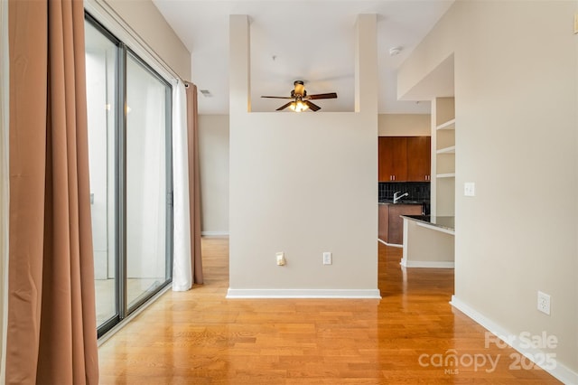 unfurnished room featuring baseboards, a ceiling fan, and light wood-style floors