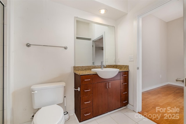 bathroom with toilet, vanity, and baseboards