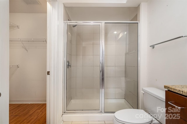 full bathroom with vanity, wood finished floors, visible vents, a stall shower, and toilet