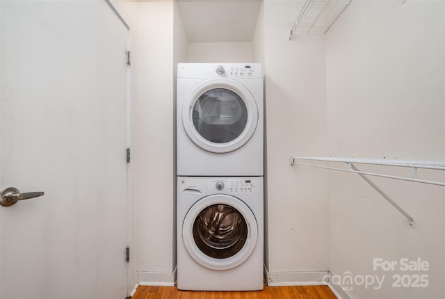 washroom featuring stacked washer / drying machine, light wood-style floors, and laundry area