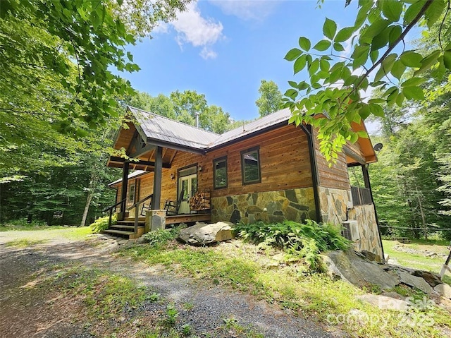 exterior space featuring stone siding, french doors, metal roof, and driveway