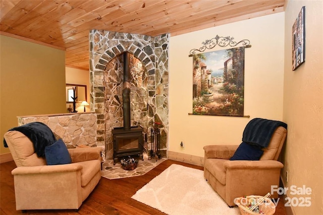 living area featuring wooden ceiling, wood finished floors, a wood stove, and baseboards