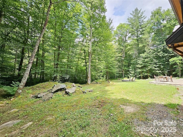 view of yard featuring a patio and a forest view