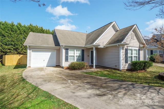 view of front of home with driveway, a front lawn, an attached garage, and fence