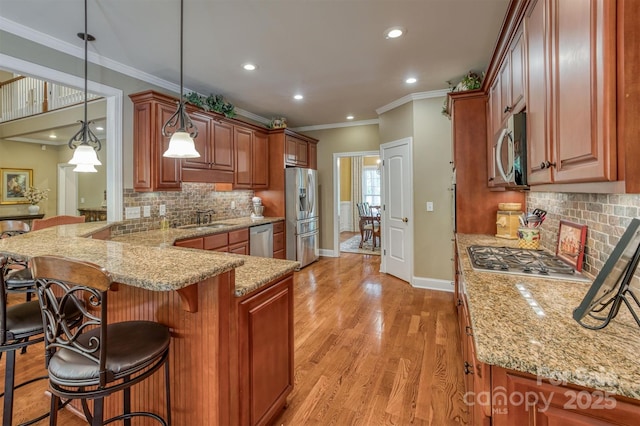 kitchen with a peninsula, a sink, appliances with stainless steel finishes, light wood-type flooring, and light stone countertops