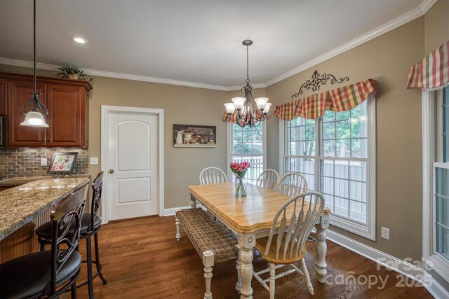 dining room featuring dark wood-style floors, ornamental molding, baseboards, and an inviting chandelier