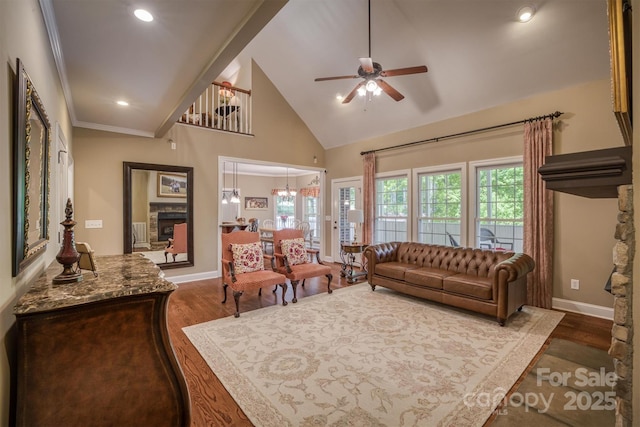 living area featuring high vaulted ceiling, a stone fireplace, wood finished floors, and baseboards