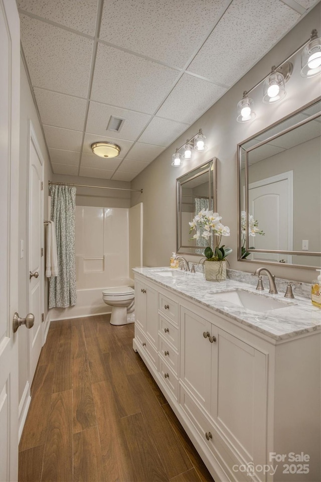 bathroom featuring wood finished floors, a sink, toilet, and shower / tub combo with curtain