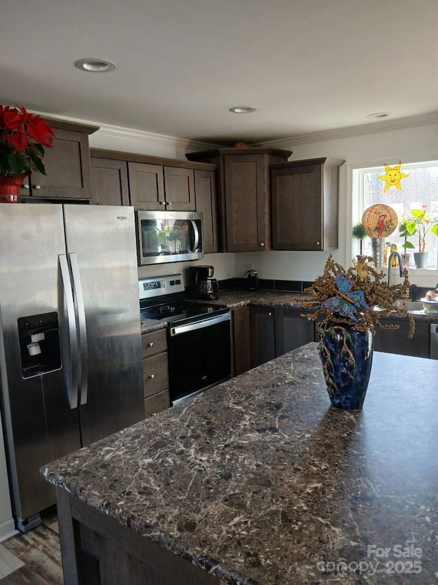 kitchen with stainless steel appliances, a sink, dark brown cabinetry, and crown molding