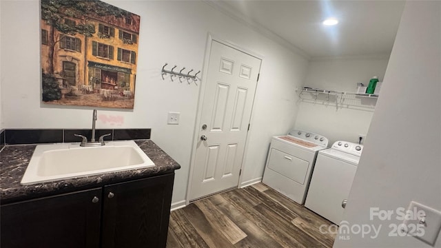 laundry area featuring laundry area, dark wood-style flooring, crown molding, washing machine and dryer, and a sink