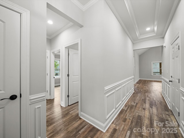 hallway with a wainscoted wall, dark wood finished floors, recessed lighting, crown molding, and a decorative wall