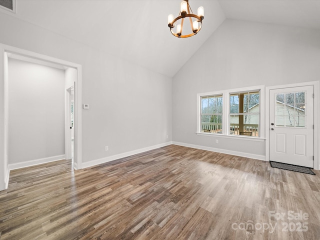 unfurnished living room featuring wood finished floors, baseboards, visible vents, high vaulted ceiling, and a chandelier