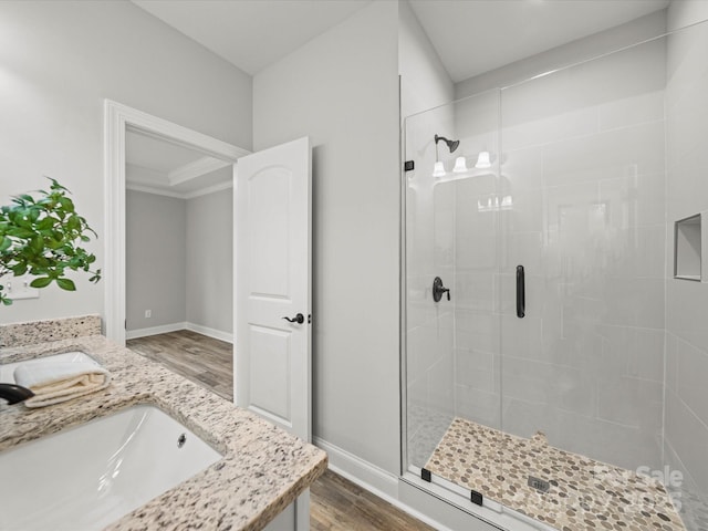 bathroom with a sink, baseboards, wood finished floors, and a stall shower