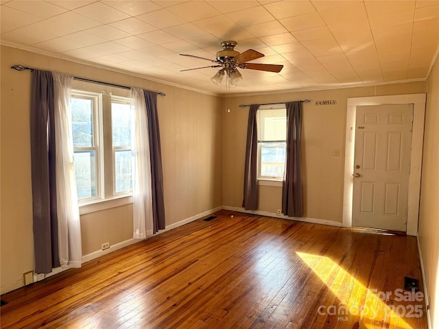 spare room featuring a healthy amount of sunlight, crown molding, and hardwood / wood-style floors