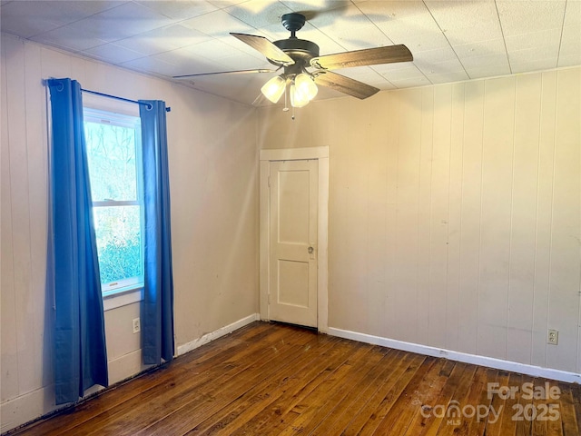 spare room featuring dark wood-style flooring, ceiling fan, and baseboards