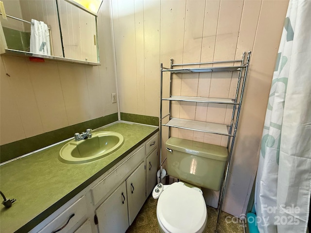 full bath featuring curtained shower, wood walls, vanity, and toilet