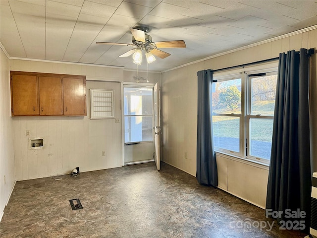 interior space with ornamental molding, ceiling fan, wooden walls, and tile patterned floors