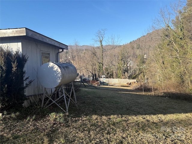 view of yard with a wooded view and fence