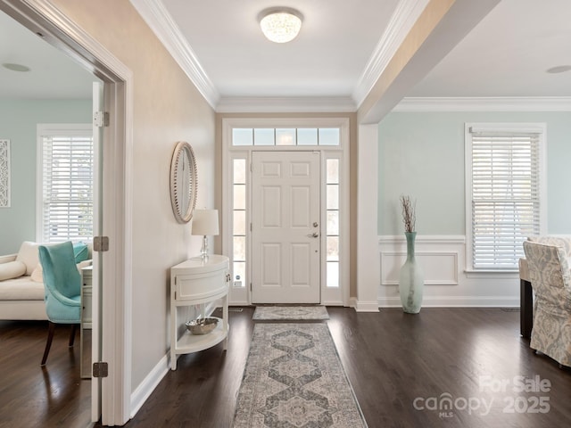 foyer with a wainscoted wall, crown molding, and dark wood-style flooring