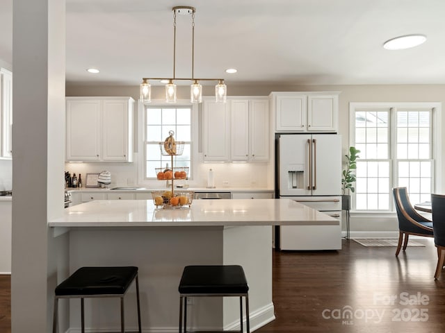 kitchen featuring a breakfast bar area, dark wood-style floors, light countertops, white cabinets, and white refrigerator with ice dispenser