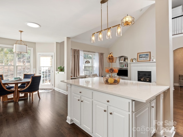 kitchen with dark wood finished floors, open floor plan, vaulted ceiling, hanging light fixtures, and white cabinetry