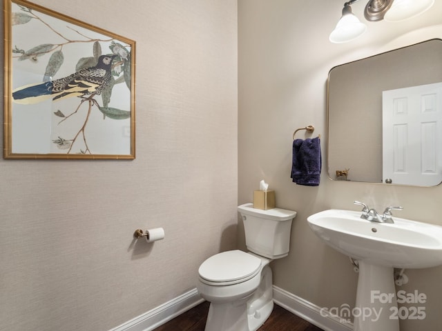 half bath featuring toilet, wood finished floors, and baseboards