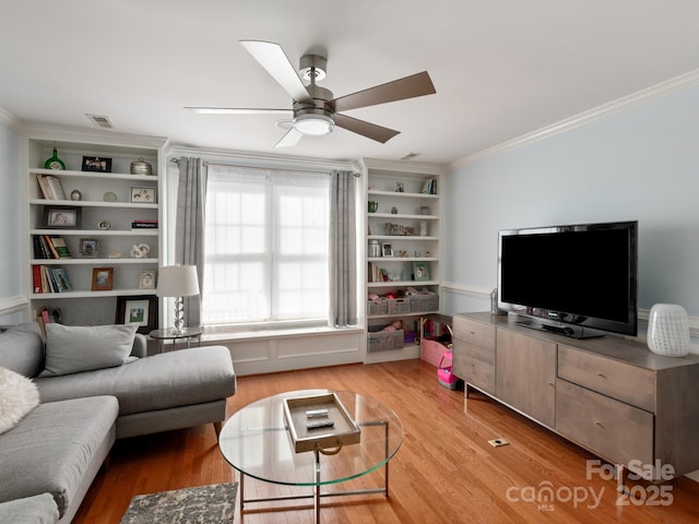 living room featuring crown molding, a ceiling fan, visible vents, and light wood-type flooring