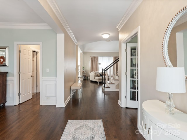 entryway with dark wood-type flooring, stairway, a wainscoted wall, and ornamental molding