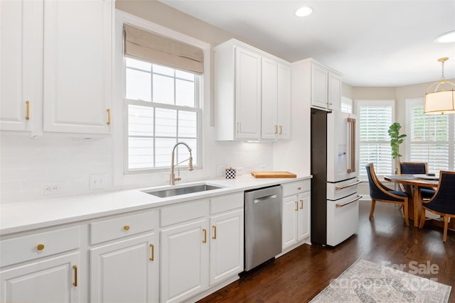 kitchen featuring white cabinets, stainless steel dishwasher, dark wood-style floors, a sink, and high end white refrigerator