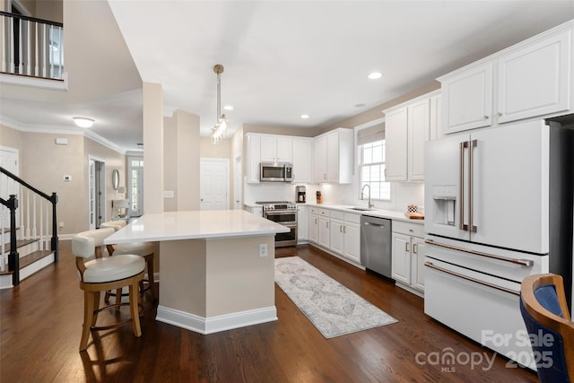 kitchen featuring white cabinets, recessed lighting, a sink, baseboards, and appliances with stainless steel finishes
