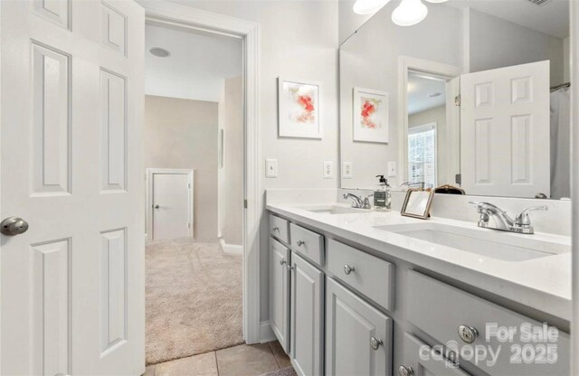 full bath featuring double vanity, tile patterned floors, and a sink