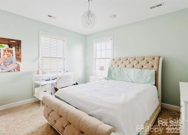 carpeted bedroom with baseboards, visible vents, and a chandelier