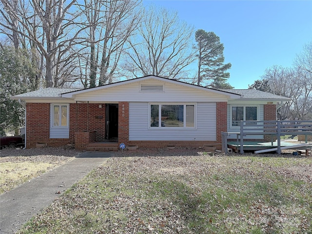 view of front facade with covered porch, brick siding, and roof with shingles