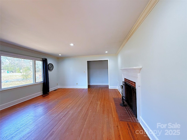 unfurnished living room featuring baseboards, wood finished floors, crown molding, a fireplace, and recessed lighting