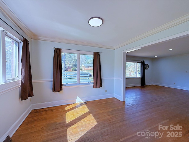 empty room featuring crown molding, baseboards, and wood finished floors