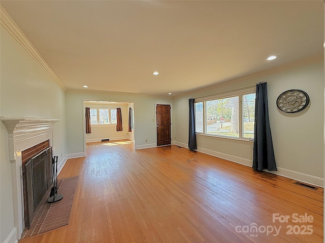 unfurnished living room with a fireplace, visible vents, light wood-style floors, ornamental molding, and baseboards