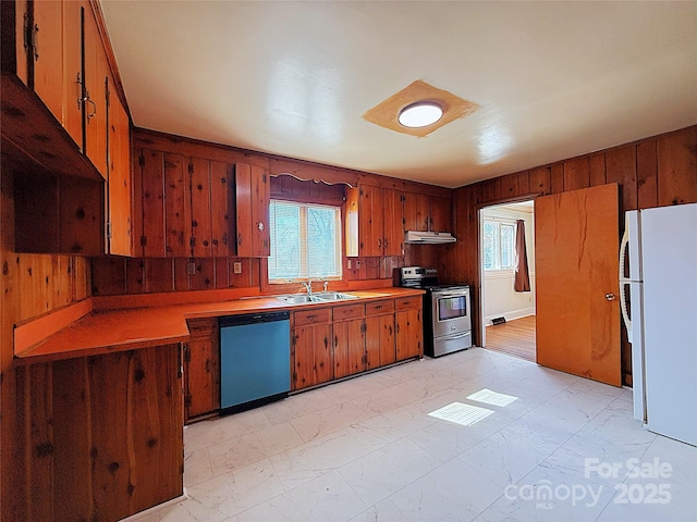 kitchen with dishwasher, freestanding refrigerator, wood walls, stainless steel range with electric stovetop, and a sink