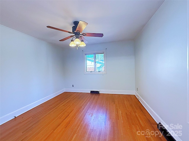 empty room featuring light wood-style floors, visible vents, baseboards, and ceiling fan