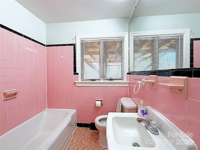 full bath with toilet, tile patterned flooring, a sink, and tile walls