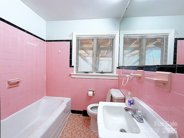 full bath with a healthy amount of sunlight, tile walls, toilet, and a tub