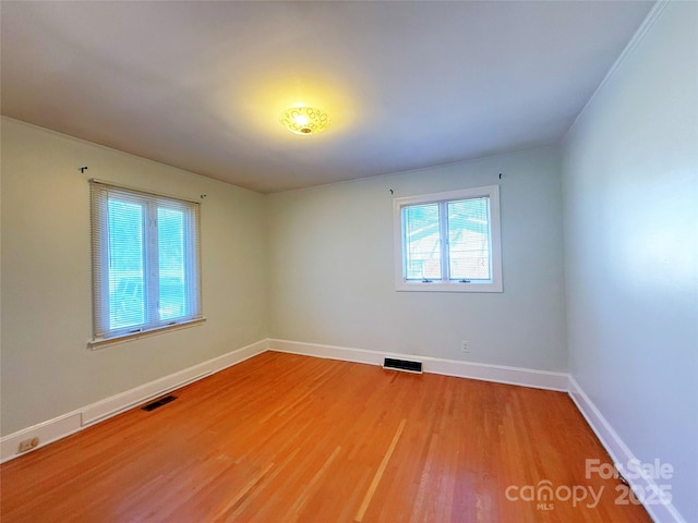 empty room featuring baseboards, visible vents, and light wood-style floors