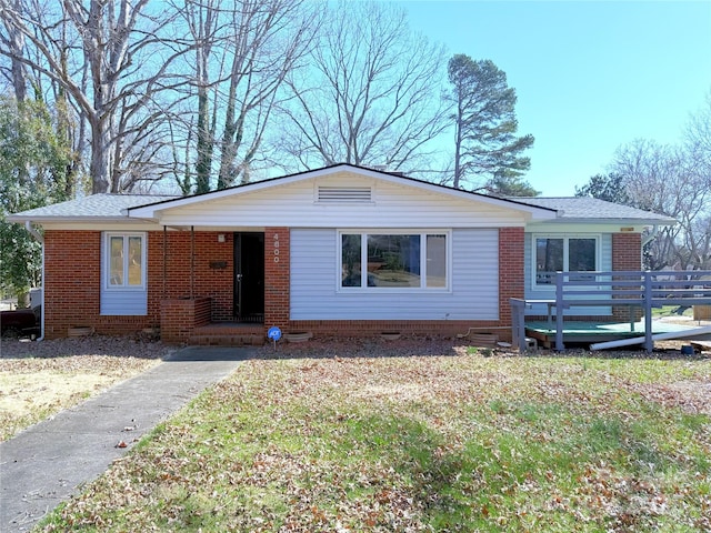 view of front of home with roof with shingles, crawl space, a front lawn, a porch, and brick siding