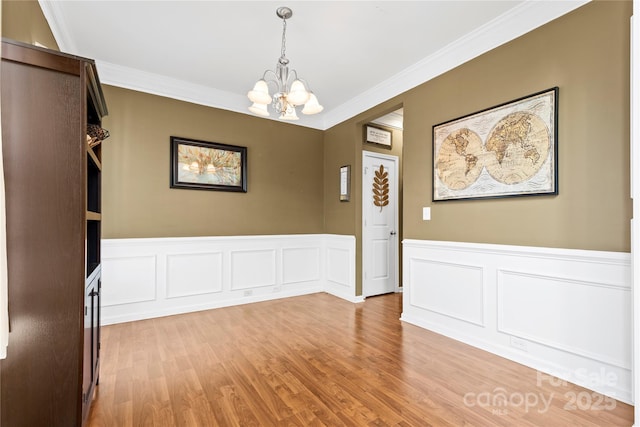 unfurnished dining area featuring a chandelier, crown molding, and light wood-style floors