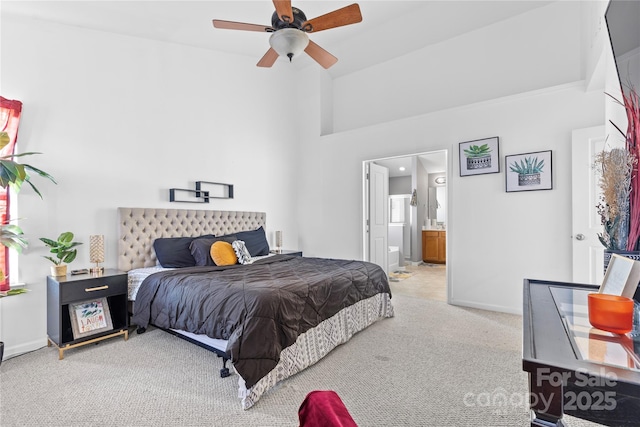 carpeted bedroom with ensuite bath, baseboards, and a ceiling fan