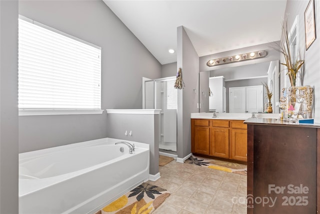 bathroom featuring double vanity, a stall shower, a garden tub, vaulted ceiling, and a sink