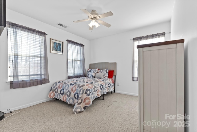 carpeted bedroom with a ceiling fan, visible vents, and baseboards