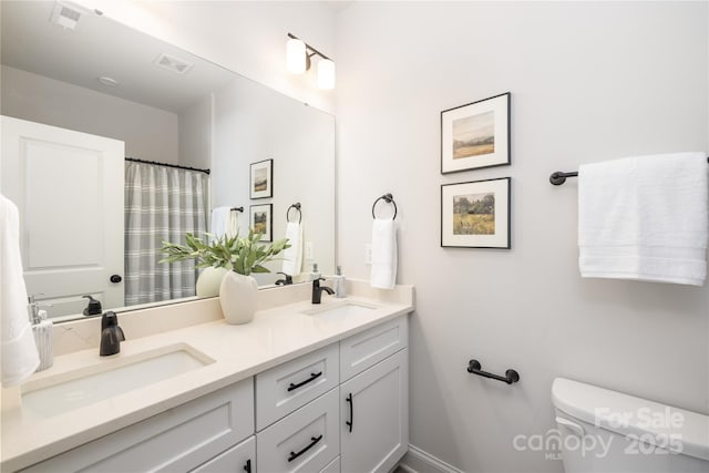 full bath featuring double vanity, visible vents, toilet, and a sink